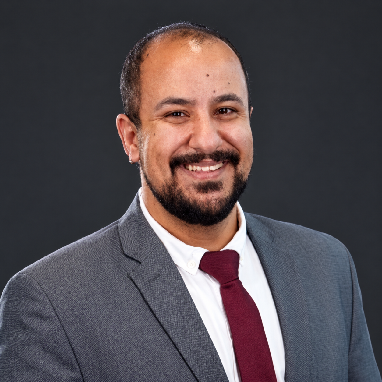 Khaled Nasr wearing a grey suit and burgundy tie